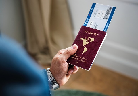 A hand holds a passport with an enclosed airline ticket 
