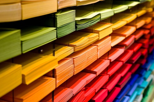 Series of paper trays containing different coloured paper. Each colour is arranged horizontally forming a rainbow like pattern.