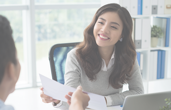 Employee sitting in front of window hands colleague a sheet of paper