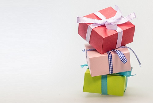 A green, pink and red present tied with bows stacked against a white background