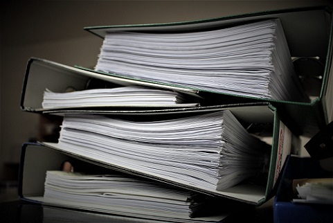 Stacked filled green lever arch files on a desk