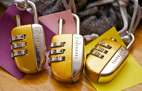 Three combination locks with colour coded tags rest on a wooden desk