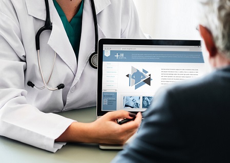 A doctor shows a patient a website on a laptop