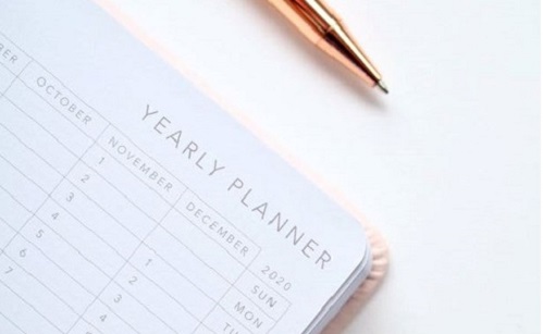 Gold pen and year planner open on a white background