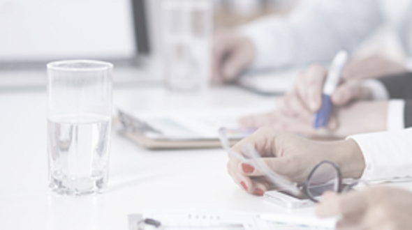 Employee hands resting on papers at a desk with glasses of water